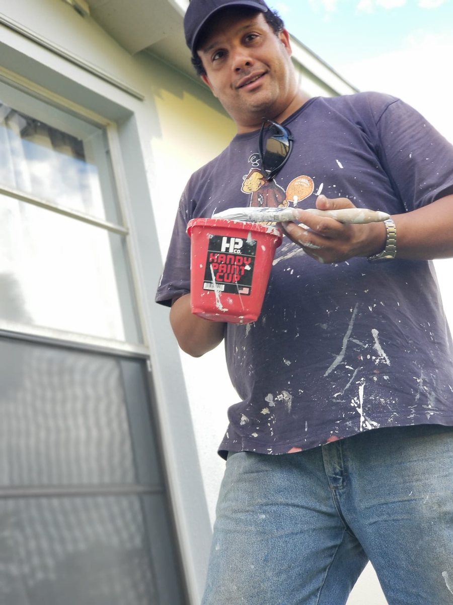 Jürgen de Clercq mid-project, paint bucket in hand, on a house exterior